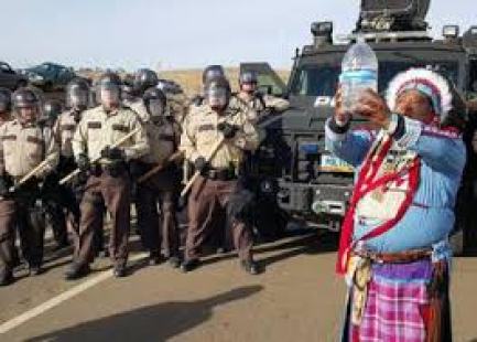 Water Protector praying with water in the face of militarized police in Standing Rock.